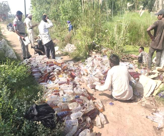 शराब की बोतलों और पेटियों की गिनती करते पुलिस कर्मी।