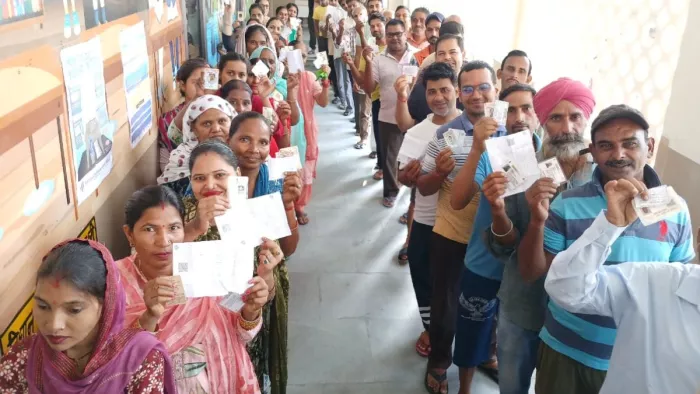 मतदान केंद्र पर वोट डालने के लिए इंतजार करते मतदाता।