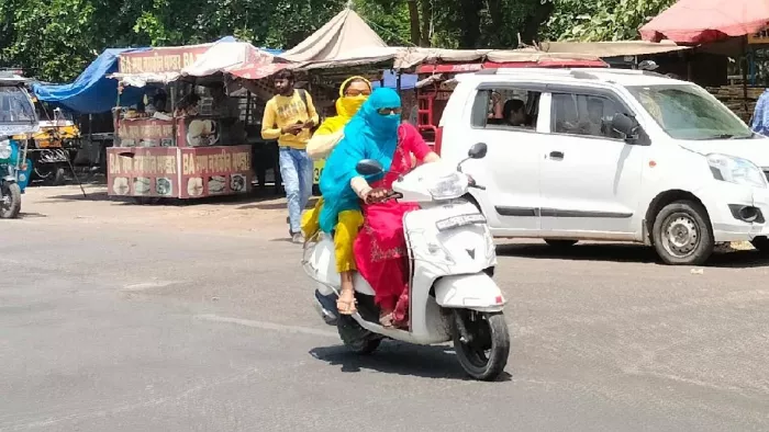 चिलचिलाती धूप में युवतियां सिर पर दुपट्टा ओढ़कर स्कूटी पर सवार होकर गंतव्य की ओर जाती हुई। जागरण।