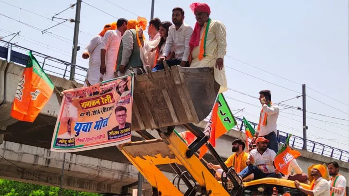 जनकपुरी-राजौरी रोड पर नामांकन रोड शो के दौरान बुलडोजर पर लोग। जागरण