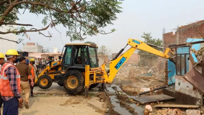 रटौल में मकानों को तोड़ता प्रशासन का बिल्डोजर और मौजूद भीड़