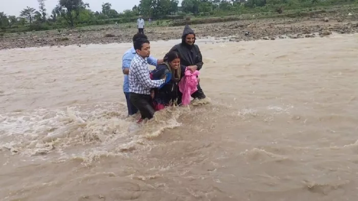 उफनाती सूखी नदी में खिमुली देवी को पार कराते ग्रामीण। सौ पंकज कोटियाल