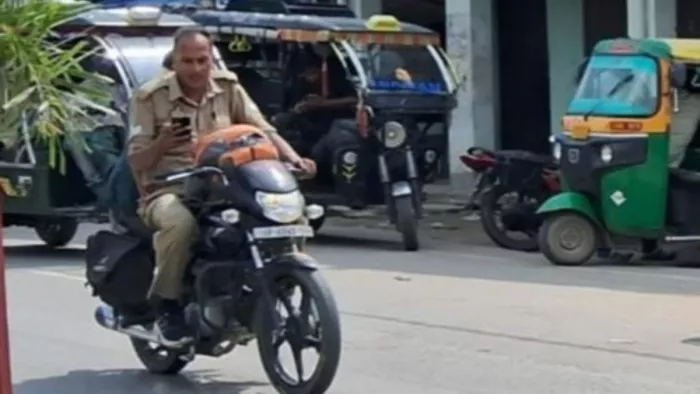 शहजादपुर में बिना हेलमेट के मोबाइल देखते हुए एक हाथ से बाइक चलाता पुलिसकर्मी-जागरण