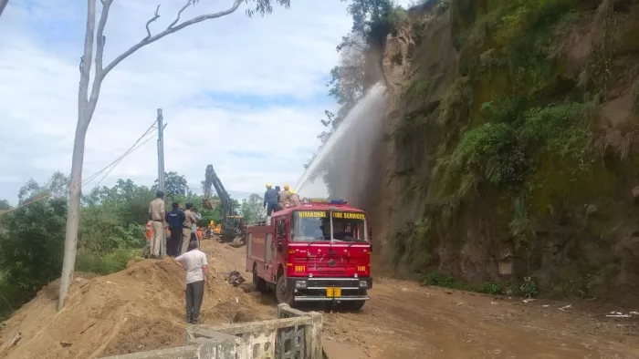 बिलासपुर के भल्लू में पानी की बौछार से गिरने के कगार पर हिस्से को फेंकने का प्रयास करते दमकल कर्मी।