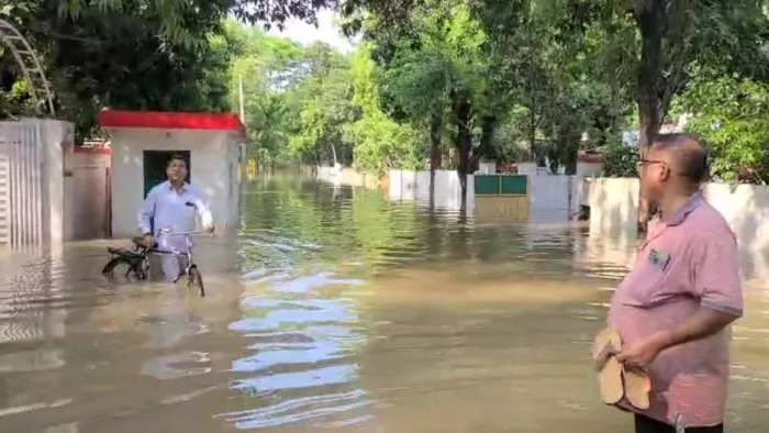 कलेक्ट्रेट रोड पर आए पानी के बीच से निकलते लोग। जागरण।