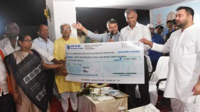 निगमकर्मियों के लिए चेक देते डिप्टी सीएम तेजस्वी यादव। जागरण