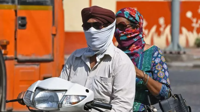 धूप से बचने के लिए चेहरा ढककर गुजरता स्कूटी चालक। फाइल फोटो- जागरण