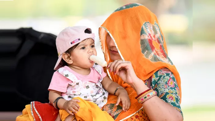 मंगलवार को नई दिल्ली में एक मां अपने बच्चे को गर्मी में आइसक्रीम खिलाती हुई (फोटो- एएनआई)