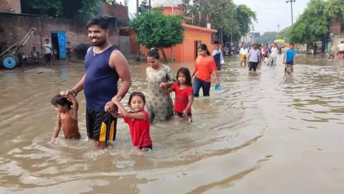 खन्नौत नदी का जलस्तर बढ़ने से शहर की सड़कों पर आए पानी के बीच से निकलते लोग व बच्चे। जागरण।