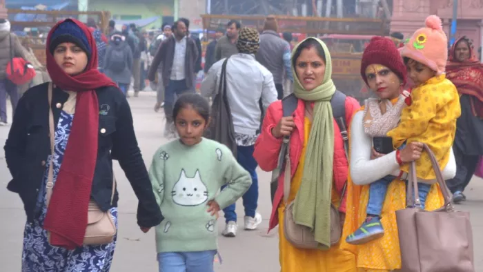 रविवार को सर्दी से बचने के लिए गर्म कपड़े पहनकर जाते बच्चे और महिलाएं। फोटो जागरण