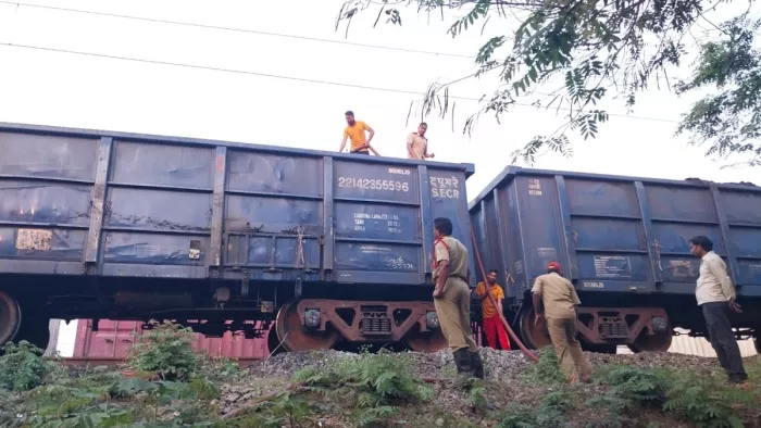 मालगाड़ी के कोयला लदे डिब्बे में लगी आग को बुझाते दमकल कर्मी।