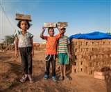 सिर पर ईंट ढोते हुए छोटे बच्चे