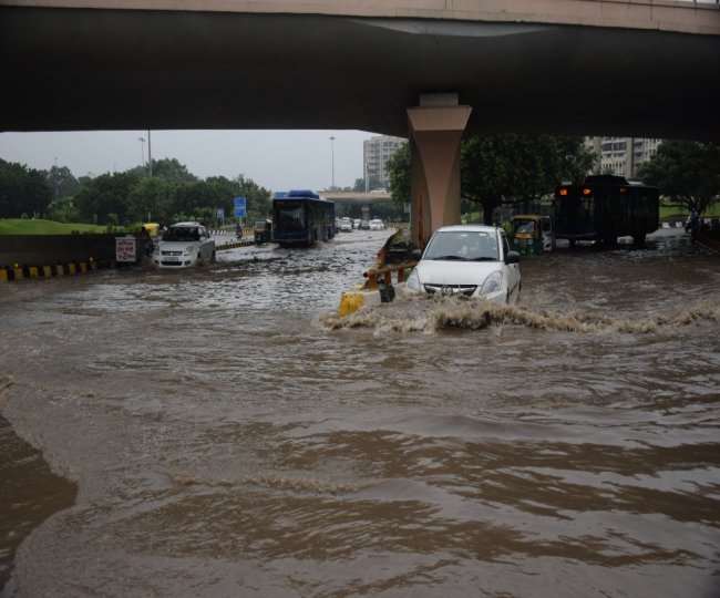 एम्स फ्लाईओवर के नीचे भरे पानी से गुजरते वाहन सवार।