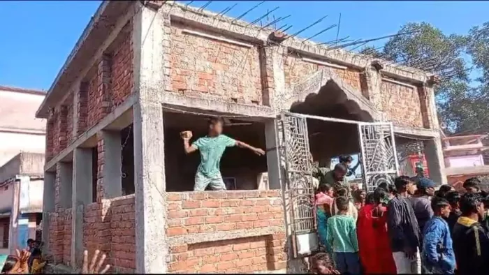 घटनास्थल पर जमा भीड़ और पत्थर फेंकता युवक