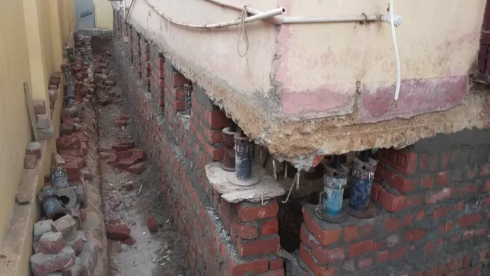 घर को जैक के सहारे ऊपर उठाए जाने की तस्वीर