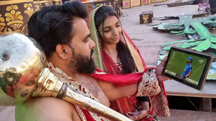रामलीला मंच पर पूर्वाभ्यास के दौरान टैब पर क्रिकेट मैच देखते कलाकार। फोटो- जागरण