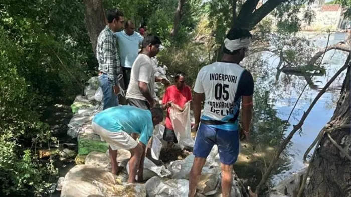 मुंगेशपुर ड्रेन के तटबंधों को ऊंचा करने में जुटे कामगार। जागरण