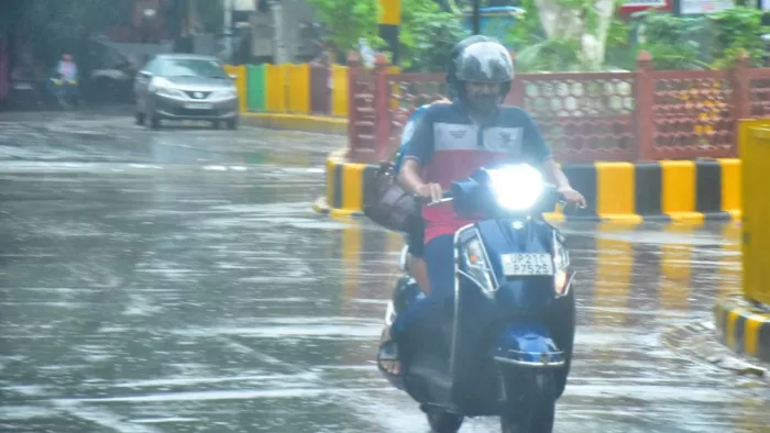 UP Weather Update: मुरादाबाद में शनिवार सुबह बारिश के बीच निकलता स्कूटी सवार युवक। जागरण