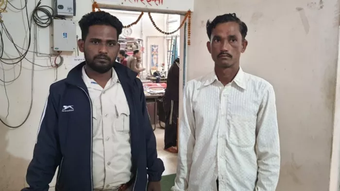 डार्क ब्लू जैकेट पहने हुए पुलिस कर्मचारी के साथ सफेद रंग की शर्ट में गिरफ्तार आरोपित। फोटो- जागरण