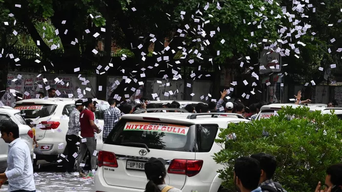 नई दिल्ली-डूसू चुनाव के लिए नार्थ कैंपस में चुनाव प्रचार के दौरान कारों के काफिले से पर्चे उड़ाते हुए छात्र।