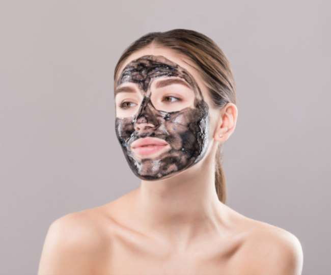 फेस पर चारकोल फेस पैक लगाए महिला