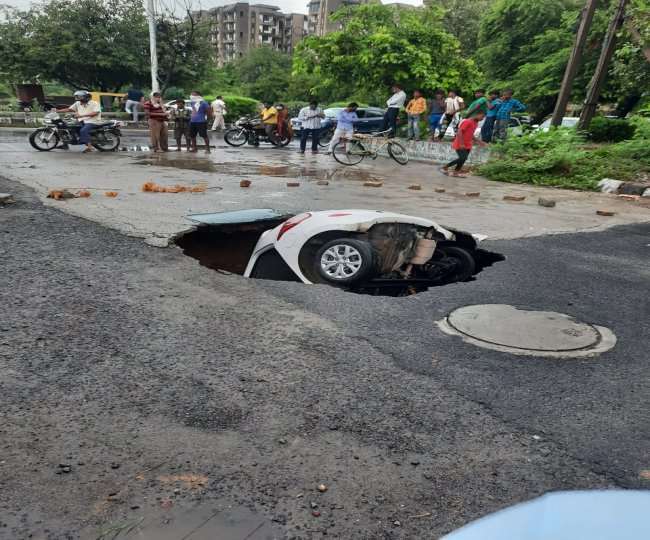 द्वारका बीच सड़क गड्ढे में समाई कार। जागरण