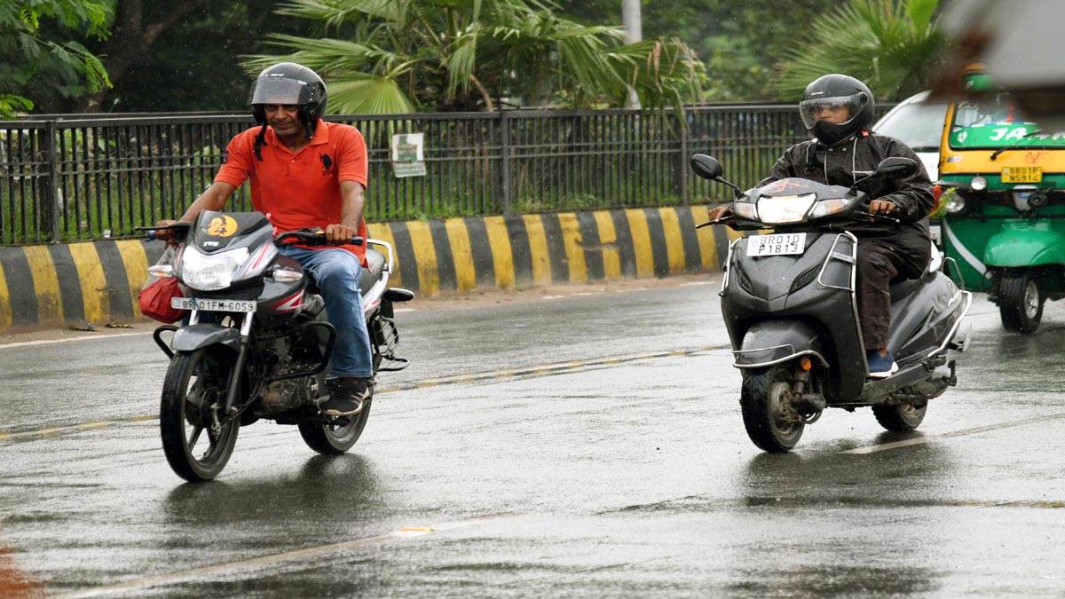 राजधानी पटना में फुहारों के बीच गुजरते बाइक सवार। जागरण