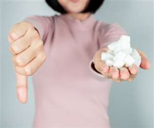 एक हाथ में चीनी का क्यूब्स लिए अंगूठा नीचे करती युवती