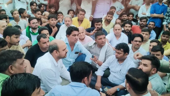 चरथावल में हक़ीमपुरा मार्ग पर धरना दे रहे लोगो के बीच बैठे अधिकारी। जागरण