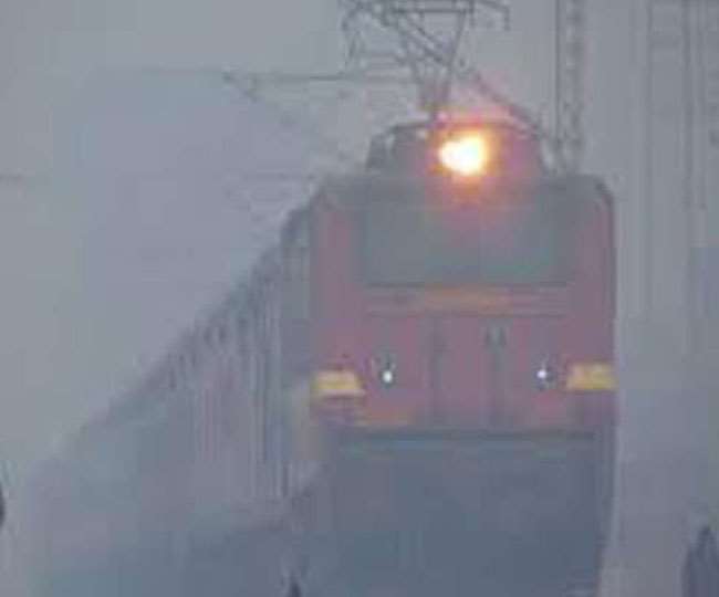 धुंध में रेलवे स्टेशन से गुजरती ट्रेन।