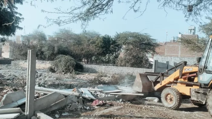इस्माइलपुर में जमीन घेरने के लिए की गई चहारदीवारी को तोड़ते हुए अर्थमूवर। जागरण
