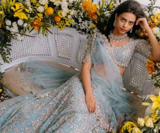 लाइट ब्लू लहंगे में बैठकर पोज़ देती युवती