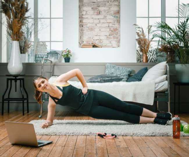 ब्लैक आउटफिट में प्लैक एक्सरसाइज करती महिला