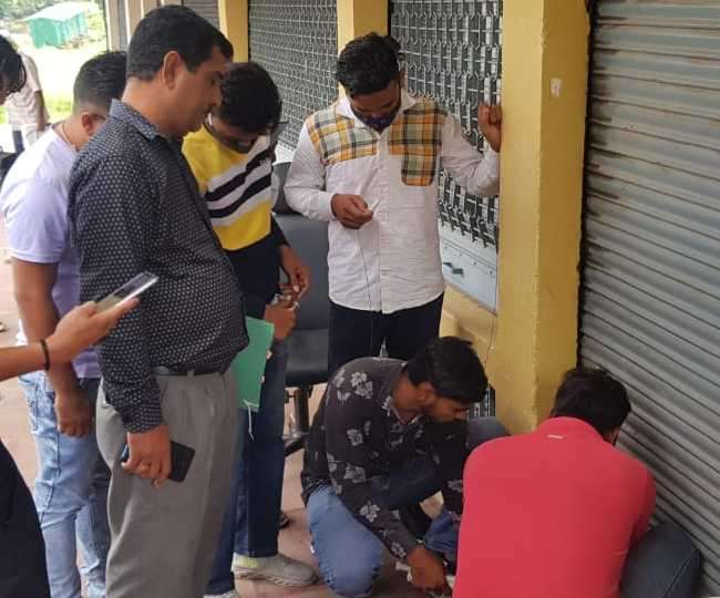 सिटी सेंटर में शोरूम को सील करते निगम के कर्मचारी।