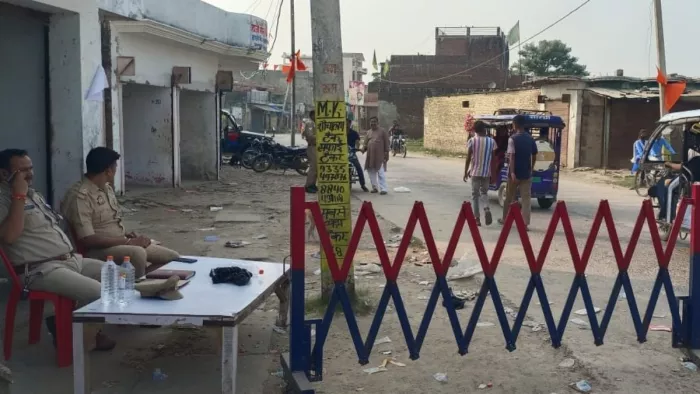 महराजगंज कस्बे में लगाई गई बैरिकेडिंग के पास सुरक्षा में बैठे पुलिस कर्मी व आवागमन करते लोग।- जागरण