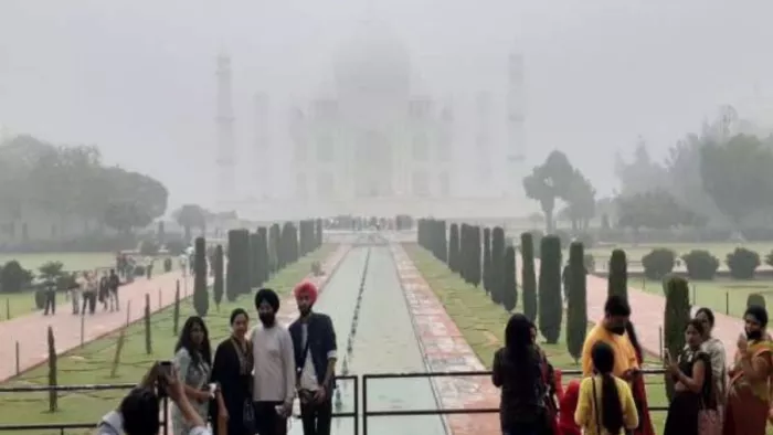 ताजमहल पर कोहरे के बीच फोटो खिंचाते पर्यटक।