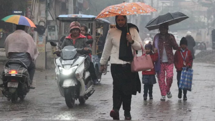 हिसार में वर्षा के दौरान अभिभावकों के साथ वर्षा से बचते हुए स्कूल में जाते विद्यार्थी। (फोटो- गुलशन बजाज)