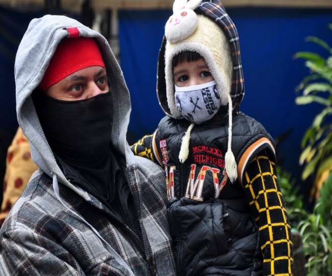 दिल्ली में पड़ रही ठंड से बचाने के लिए बच्चे को गर्म कपड़ें पहनाकर लेकर जाता पिता। ध्रुव कुमार