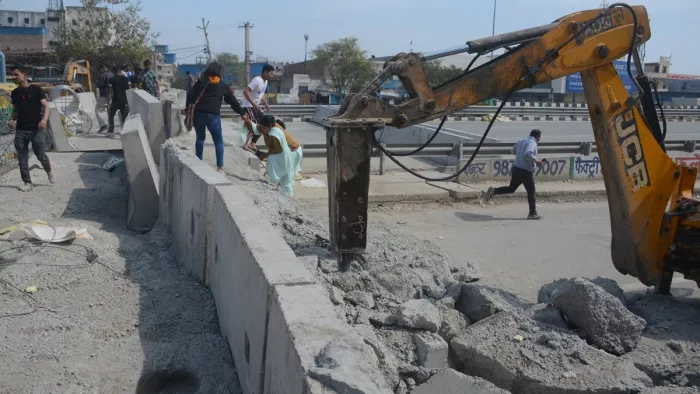 सड़क से वाहनों के लिए लेन खोलने के लिए कंक्रीट को अर्थ मुवर मशीन से तोड़ते हुए।