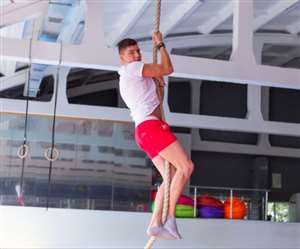 जिम में रोप क्लाइंबिंग वर्कआउट करता पुरुष