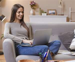 लैपटॉप पर काम कर मुस्कुराती हुई महिला