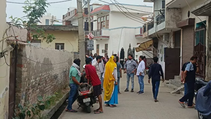 जिस मकान में आग लगी है उस गली में एकत्र लोग।