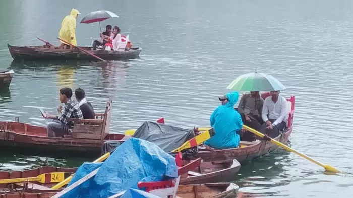 झील में छाता लेकर नाव में बैठे पर्यटक। जागरण