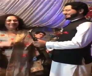 दूल्हा AK-47 को हवा में लहराकर उपहार को स्वीकार करता है।