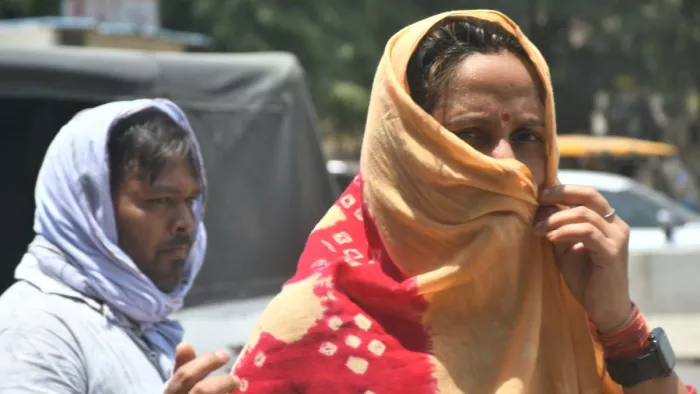 कानपुर में सूरज के तपिश से बचने के लिए मुंह ढंककर जाती महिला। जागरण