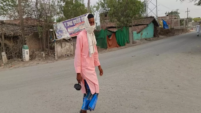 गर्मी से बचने के लिए मुंह ढंककर घर जाता व्यक्ति