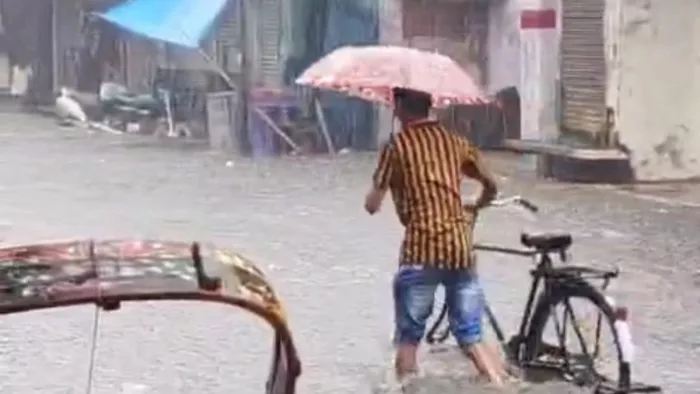 Pilibhit Weather: बारिश के बीच से निकलता युवक। जागरण।