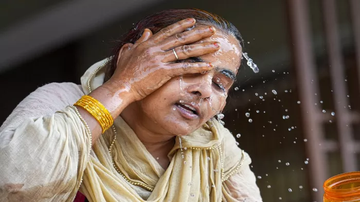 भीषण गर्मी में चेहरे पर पानी के छीेंटे मारती एक महिला