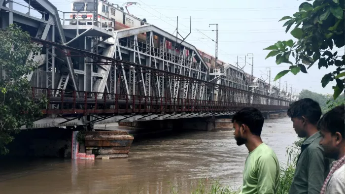 लोहे के पुल पर खतरे के निशान से ऊपर बह रही यमुना का जलस्तर देखते लोग। फोटो- ध्रुव कुमार